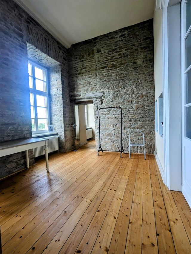 Praxisraum mit Natursteinwand und Holzdielen in der Burg Herstelle